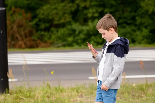 Niño jugando juegos móviles en el teléfono inteligente en la calle —  Fotos de Stock