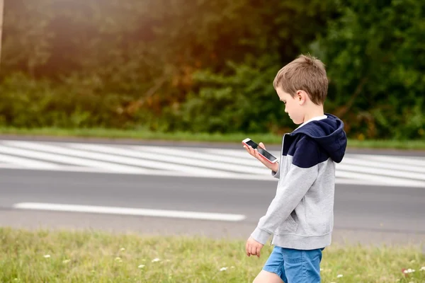 Criança jogando jogos para celular no smartphone na rua — Fotografia de Stock