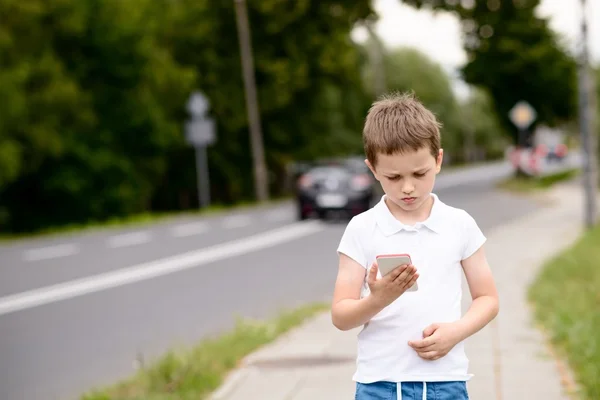Criança jogando jogos para celular no smartphone na rua — Fotografia de Stock