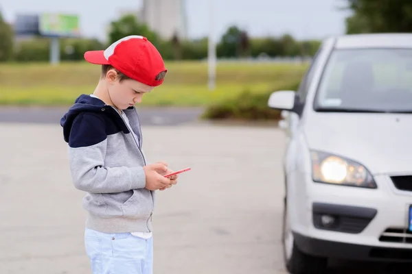 Kind spielt auf der Straße Handyspiele auf Smartphone — Stockfoto