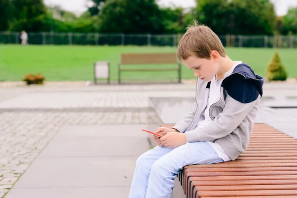 Menino criança jogando jogos móveis no smartphone — Fotografia de Stock