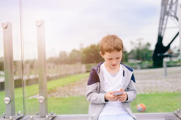 Menino criança jogando jogos móveis no smartphone — Fotografia de Stock