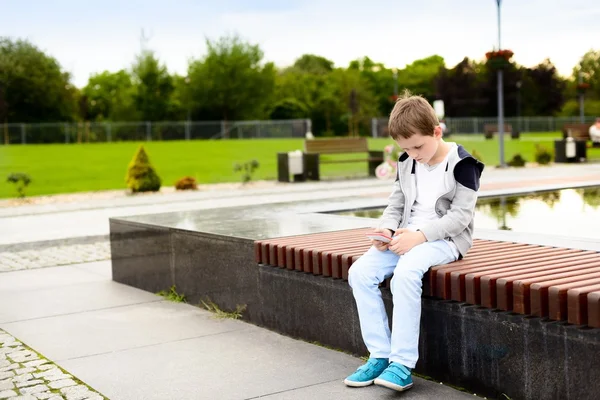 Menino criança jogando jogos móveis no smartphone — Fotografia de Stock