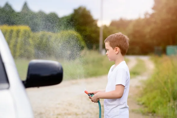 Petit garçon lavant voiture argentée dans le jardin — Photo