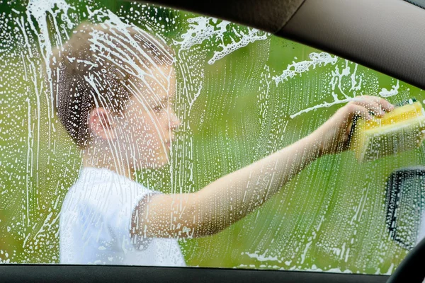 Pieni poika pesee hopeinen auto puutarhassa — kuvapankkivalokuva