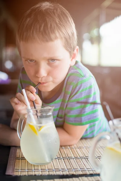 Pequeño niño de 7 años bebiendo limonada fría — Foto de Stock