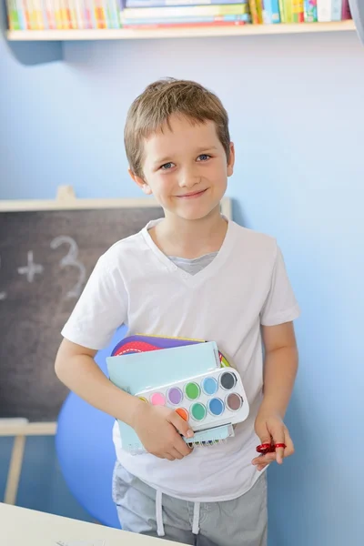 Niño de 7 años sosteniendo accesorios escolares en su mano — Foto de Stock