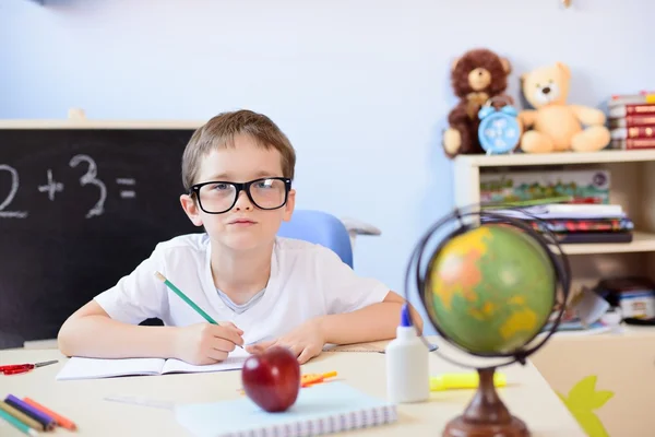 7 years old boy solves multiplication table in his copybook. — Stock Photo, Image