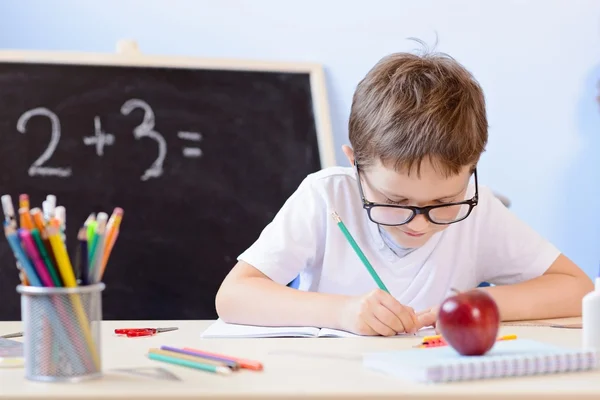 7 years old boy solves multiplication table in his copybook. — Stock Photo, Image