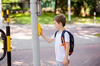 Schoolboy with backpack pressing a button on traffic clipart