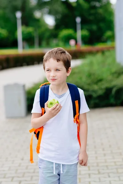 Niño comiendo manzana en el camino a la escuela . —  Fotos de Stock