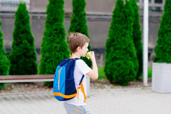Хлопчик їсть яблуко в дорозі до школи . — стокове фото