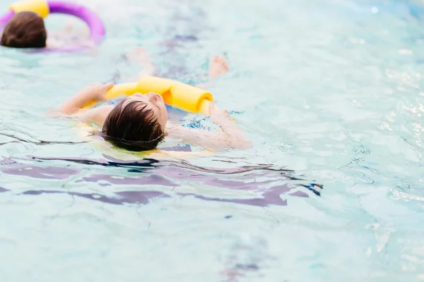 Menino de sete anos aprendendo a nadar na piscina — Fotografia de Stock