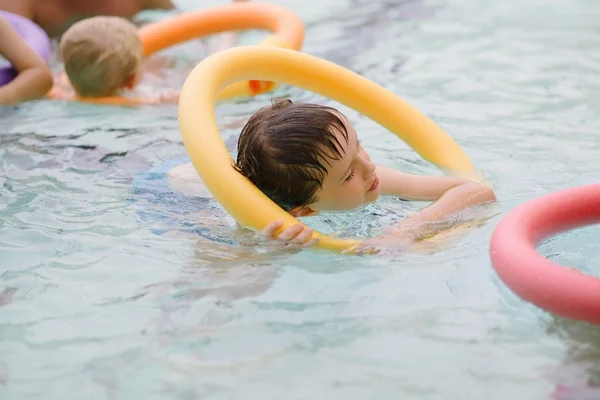 Menino de sete anos aprendendo a nadar na piscina — Fotografia de Stock