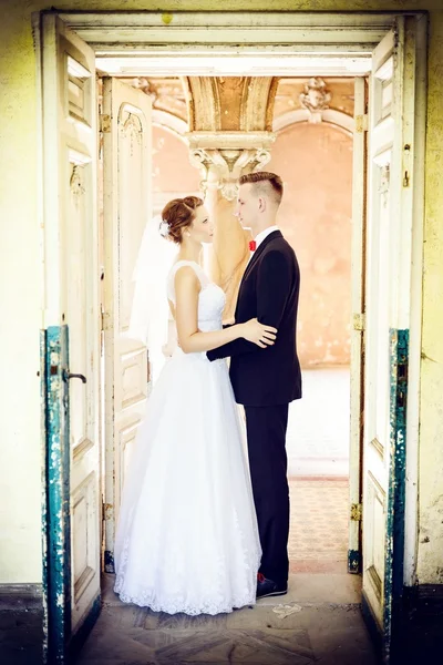 Newlyweds hugging at the door in an old house — Stock Photo, Image