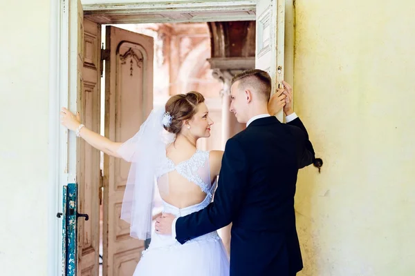 Νέοι όμορφη νύφη και ο γαμπρός κοντά παλαιά πόρτα — Φωτογραφία Αρχείου