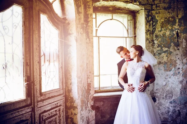 Newlyweds hugging at the door in an old house. — Stock Photo, Image