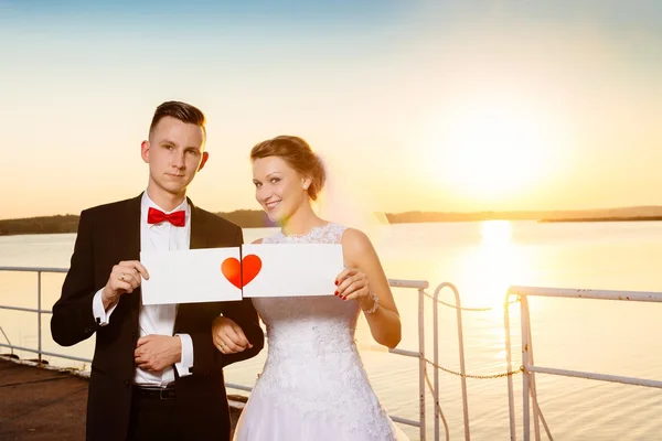 Bride and groom on the pier at sunset. — Stock Photo, Image