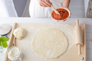 Kadın pizza üzerine domates sosu ekleme