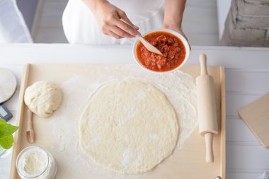 Kadın pizza üzerine domates sosu ekleme