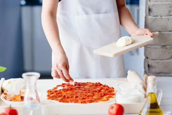 Frau legt Mozzarella-Scheiben auf die Pizza — Stockfoto