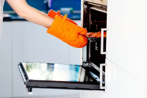 Woman pulling a pizza from electric oven — Stock Photo, Image