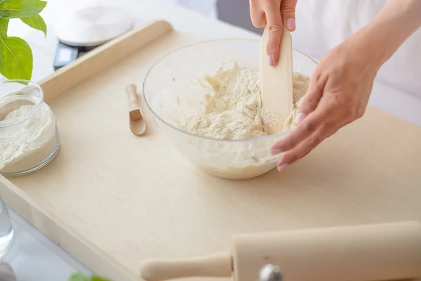 Mujer mezclando masa de pizza con espátula de madera . — Foto de Stock