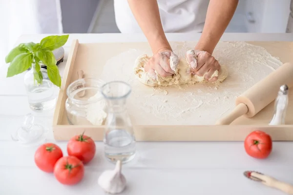 Женщина месит тесто для пиццы на деревянной доске — стоковое фото