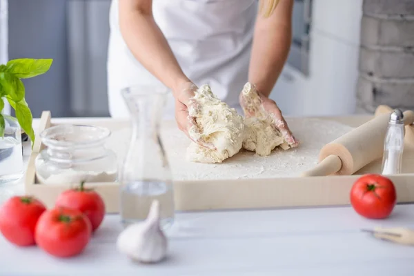Frau knetet Pizzateig auf hölzernem Backbrett — Stockfoto