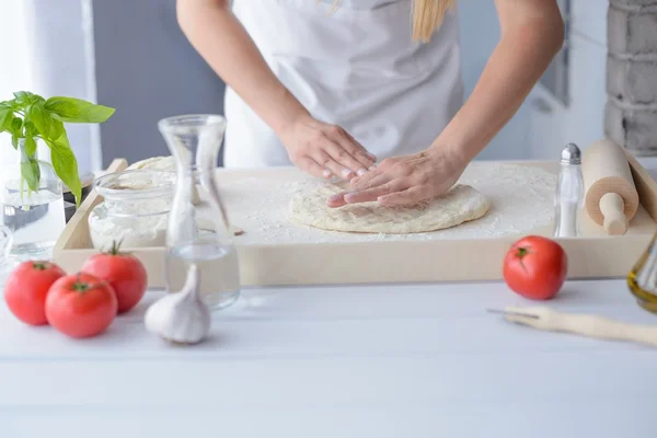 Mujer amasando masa de pizza en tablero de repostería de madera . — Foto de Stock