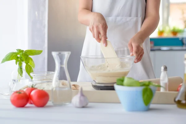 Mujer mezclando masa de pizza con espátula de madera . — Foto de Stock