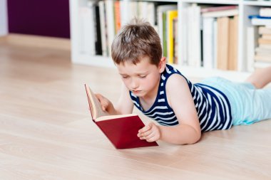 Yedi yaşında çocuk Kitaplığı'nda bir kitap okuma.