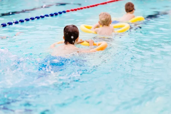 Siedem lat chłopiec nauki pływania na basenie. — Zdjęcie stockowe