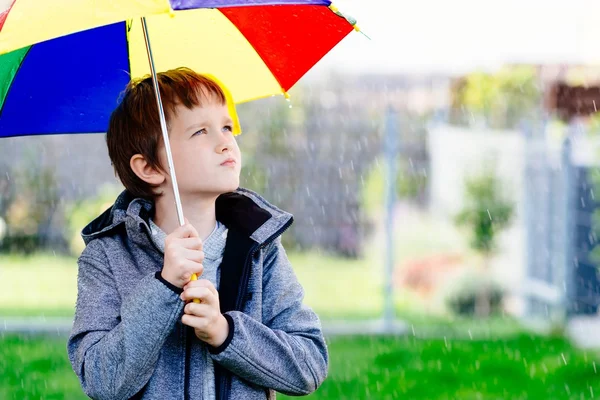 Sette anni ragazzo in piedi sotto la pioggia — Foto Stock