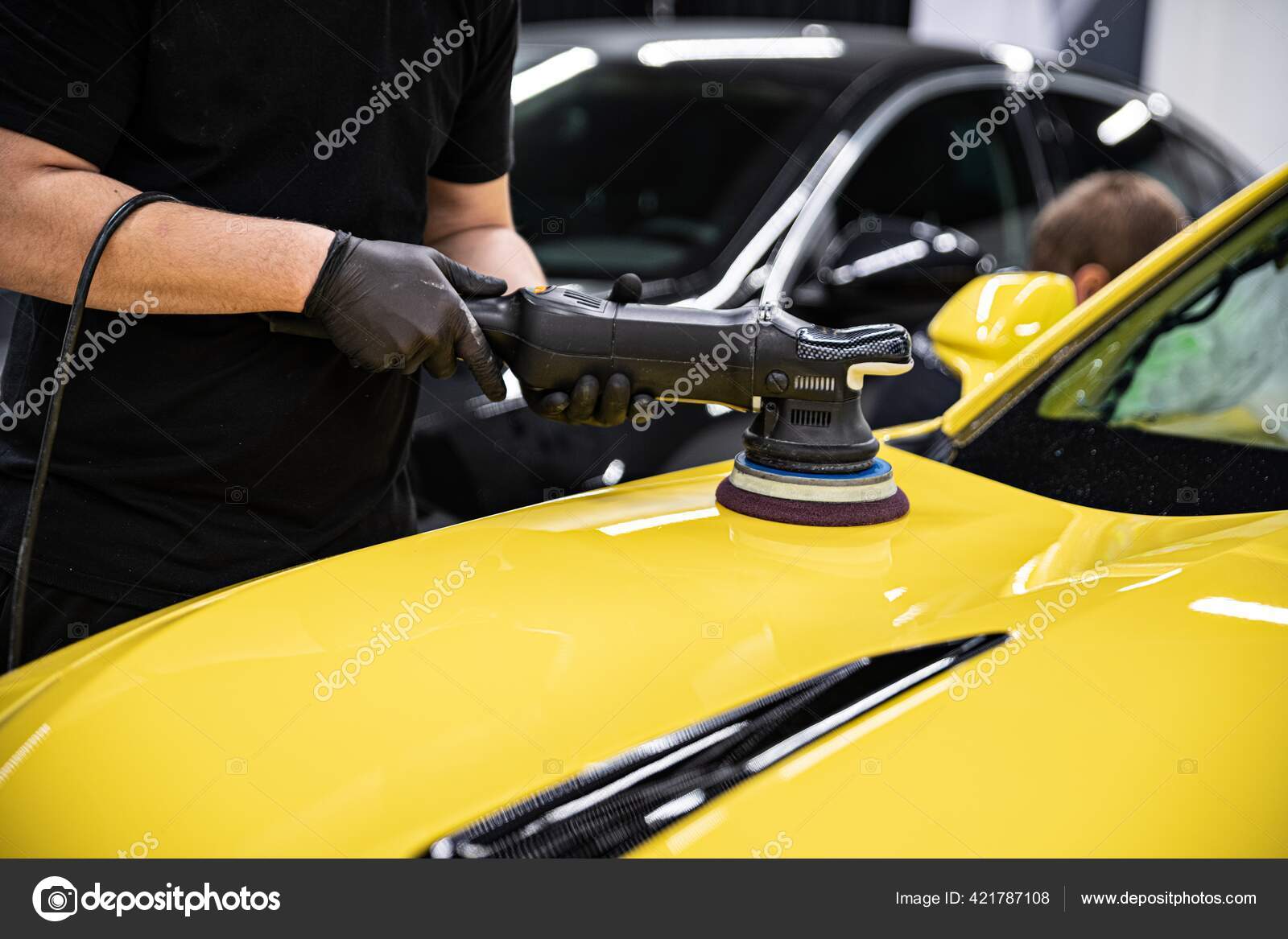 Man car detailing studio worker polishing yellow car varnish with