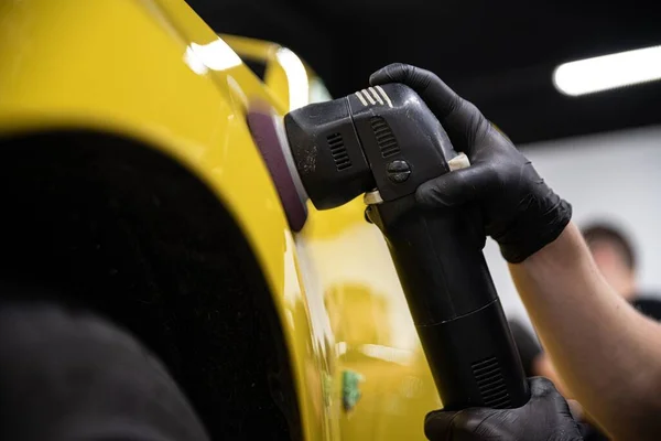 Hombre coche detallando trabajador de estudio pulido barniz de coche amarillo con pulidor eléctrico —  Fotos de Stock