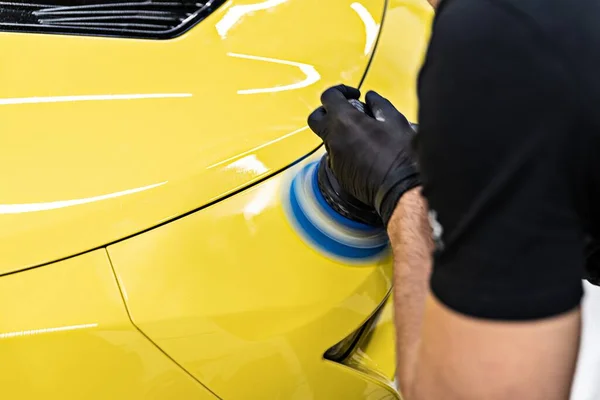 Mann im Auto: Arbeiter poliert gelben Autolack mit Elektropolierer — Stockfoto