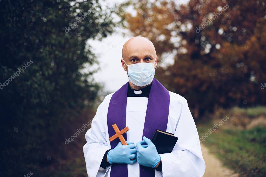 Man priest in a protective mask and protective gloves during a pastoral visit.