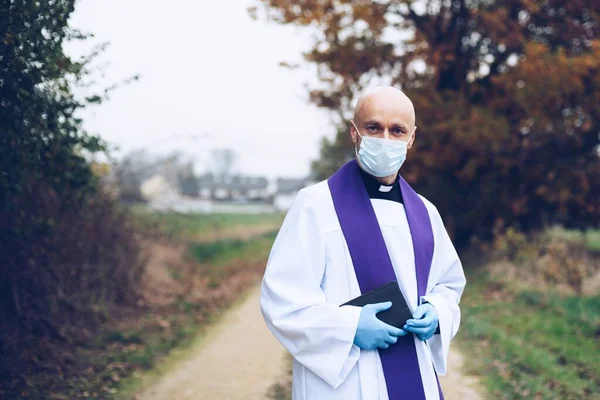Homem sacerdote em uma máscara protetora e luvas de proteção vai para visitas pastorais — Fotografia de Stock
