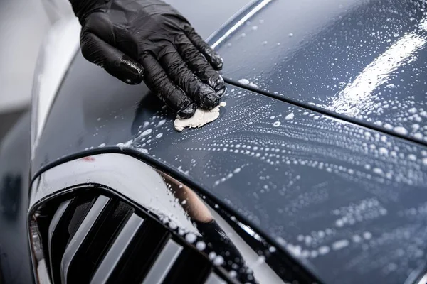 Homme lavage de voiture travailleur nettoyage vernis de voiture avec de l'argile de voiture. — Photo