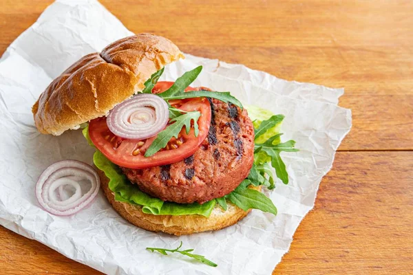 Delicious, healthy vegan burger with tomato, onion and arugula. — Stock Photo, Image