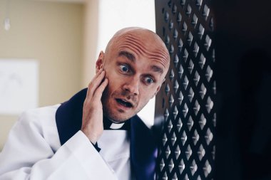 Surprised vicar priest in the confession booth clipart