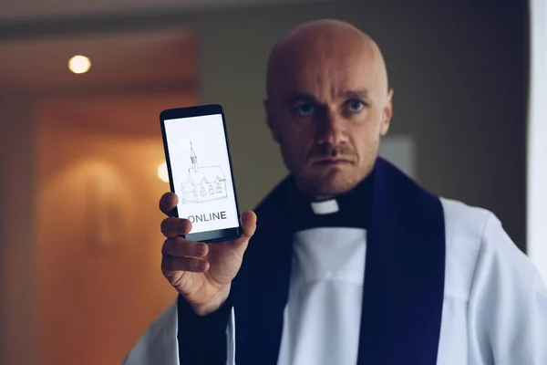 Ung präst med mobiltelefon med information för kristna. — Stockfoto