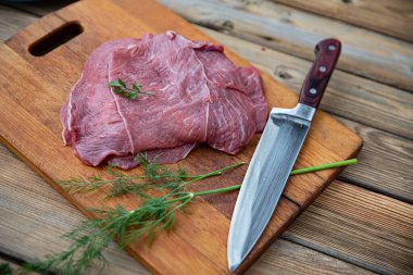 Taze çiğ et keskin bir bıçakla tahta bir tahtanın üzerinde yatıyor.