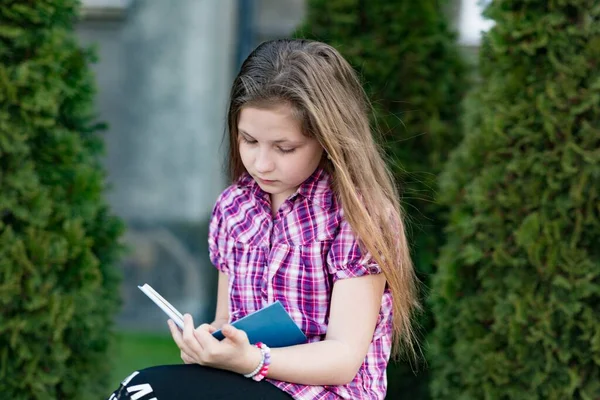 一个10岁的女孩坐在那里看书. — 图库照片