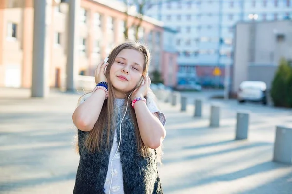 Chica joven de 10 años en auriculares escucha música con los ojos cerrados. — Foto de Stock