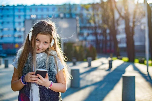 Fiatal lány zenét hallgat egy mobiltelefonról. — Stock Fotó