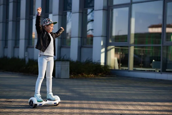 Heureuse et souriante jeune fille avec les mains en l'air monte sur hoverboard. — Photo