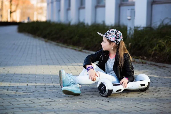 Une jeune fille de 10 ans dans un chapeau de fleur se trouve avec son hoverboard. — Photo