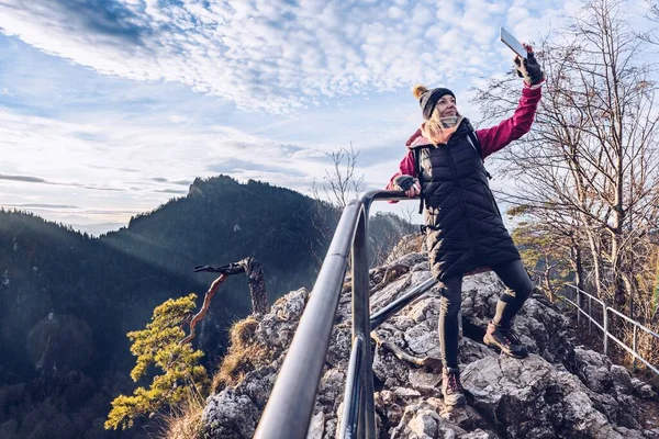 Um turista sorrindo tira uma selfie no pico da montanha. — Fotografia de Stock